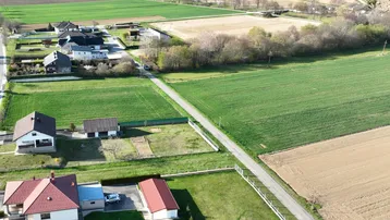 Luftaufnahme einer ländlichen Wohngegend mit Häusern, grünen Feldern und einer Zufahrtsstraße.
