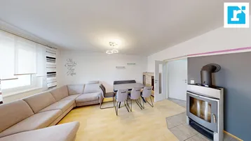 Helles Wohn- und Esszimmer mit Kaminofen, Laminatboden und gemütlicher Sitzecke.