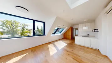 Helles Dachgeschoss-Wohnzimmer mit Holzboden, großen Fenstern und integrierter moderner Küchenzeile.