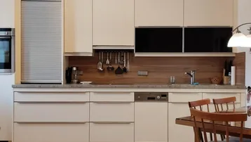 Moderne Einbauküche mit hellen Fronten, Holzakzenten und integriertem Essbereich.
