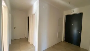 Heller Eingangsbereich mit Fliesenboden und mehreren Türen zu den angrenzenden Räumen.