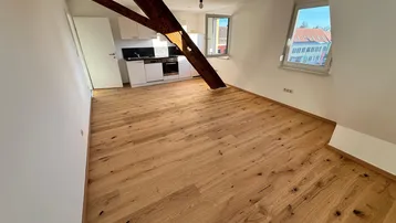 Helles Dachgeschoss-Apartment mit offener Küche, Holzbalken und neuem Parkettboden.