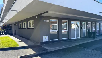 Modernes Geschäftsgebäude mit großen Fenstern und barrierefreiem Zugang über eine Rampe zum Eingang.