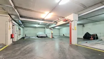 Geräumige Tiefgarage mit Betonwänden und -decken, ausgestattet mit Parklifts für mehrere Fahrzeuge.