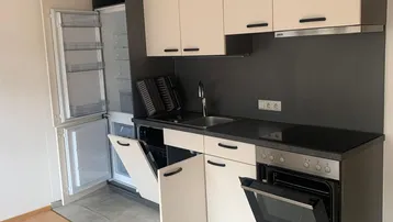 Moderne Einbauküche mit hellen Fronten, integrierten Geräten und praktischem Fliesenboden.
