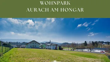 Weitläufige Grünfläche mit Blick auf die umliegende ländliche Bebauung und den blauen Himmel.