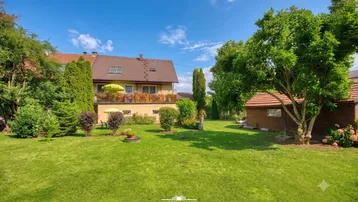 Großer gepflegter Garten mit Rasenfläche, Bäumen und Blick auf das Wohnhaus.