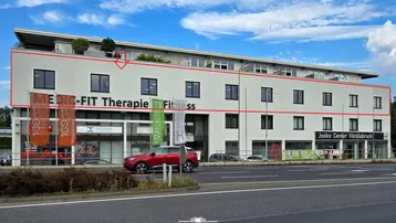 Ansicht eines modernen Geschäftsgebäudes mit weißer Fassade und roten Markierungen für die Gebäudestruktur.