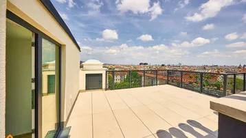Geräumige Dachterrasse mit weitem Stadtblick und moderner Brüstung unter blauem Himmel.