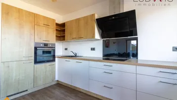 Moderne Einbauküche mit hellen Holzfronten, weißen Unterschränken und integrierten Geräten.