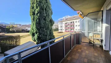 Sonniger Balkon mit Fliesenboden, Metallgeländer und einem weiten Blick auf die Berge.