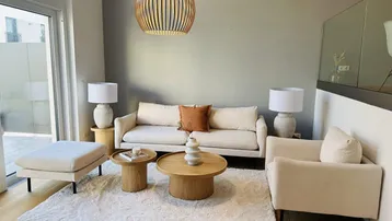Helles Wohnzimmer mit modernem Mobiliar, Holzboden und Zugang zu einem Außenbereich.