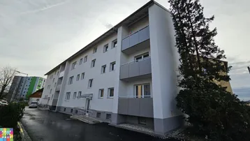 Modernes Mehrfamilienhaus mit Balkonen und barrierefreiem Zugang über eine Rampe.