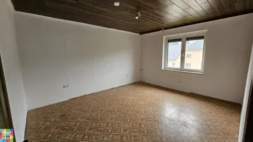 Leerer Raum mit dunkler Holzdecke und gemustertem Boden, bereit für Renovierung.