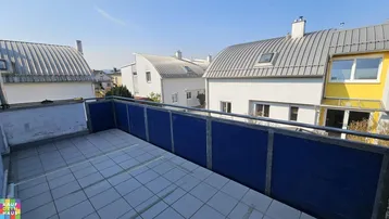 Geräumiger Balkon mit Fliesenboden und blauer Brüstung, bietet einen weiten Blick auf die umliegenden Häuser.