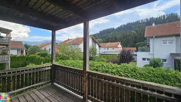 Rustikaler Holzbalkon mit Blick auf die umliegende grüne Landschaft und Berge.