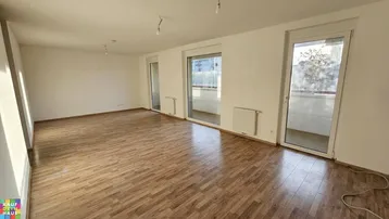 Helles Wohnzimmer mit Holzboden und Zugang zu einem Balkon, ideal für individuelle Gestaltung.