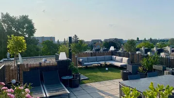 Geräumige Dachterrasse mit Lounge-Bereich, Sonnenliegen und Blick über die Stadt.