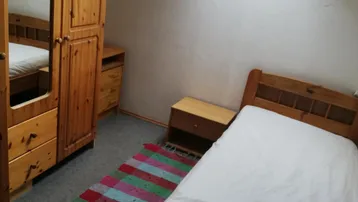 Schlafzimmer im Dachgeschoss mit Holzkleiderschrank, Bett und Dachfenster für natürliches Licht.