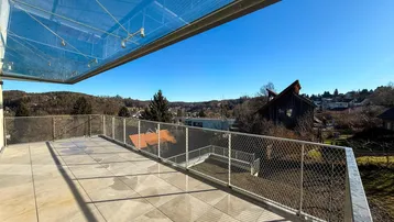 Geräumige Terrasse mit Glasüberdachung und weitem Blick über die grüne Landschaft.