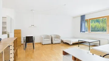 Helles Wohnzimmer mit Parkettboden, großem Fenster und Blick ins Grüne.