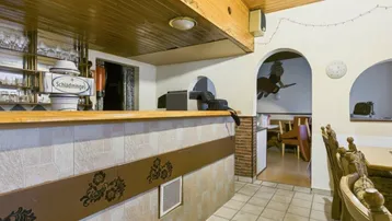 Innenansicht eines Gastraums mit Theke, Zapfanlage und rustikaler Holzdecke, bereit für Gäste.