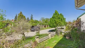Blick vom Vorgarten auf die ruhige Wohnstraße mit Bäumen und Grünflächen.