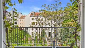 Blick vom Balkon auf die umliegenden Gebäude und viel Grün in der Stadt.