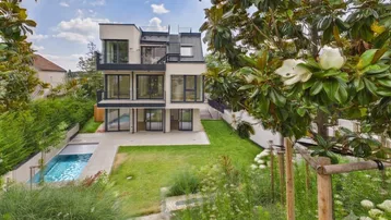 Modernes Wohnhaus mit Garten, privatem Pool und mehreren Balkonen in grüner Umgebung.