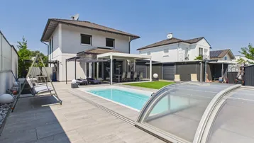 Großzügiger Außenbereich mit Pool, Liegeflächen und überdachter Terrasse, ideal für Entspannung und Unterhaltung.