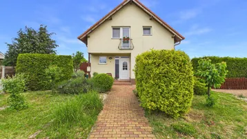 Kleines Einfamilienhaus mit Satteldach, gepflegtem Vorgarten und einem französischen Balkon im Obergeschoss.
