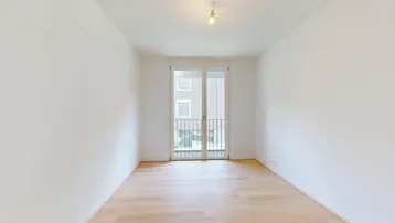 Helles Zimmer mit Holzfußboden und französischem Balkon, bietet Blick auf die Umgebung.