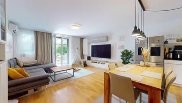 Heller offener Wohn-Essbereich mit Holzboden, modernem Sofa und Zugang zur Terrasse.