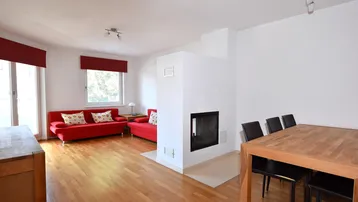 Heller Wohn- und Essbereich mit Kamin, roten Sofas und Holzboden, ideal für gemütliche Stunden.