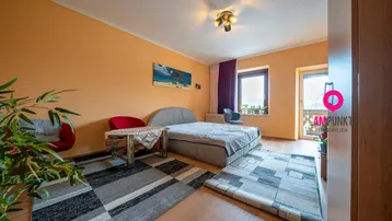 Helles Schlafzimmer mit Holzboden, orangefarbenen Wänden und Zugang zu einem Balkon.
