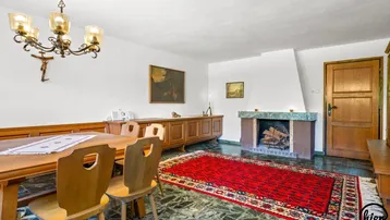 Traditioneller Essbereich mit Holztisch, Stühlen, Kamin und dunklem Steinboden.