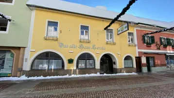 Historisches gelbes Gebäude mit Rundbogenfenstern und schneebedecktem Dach in einer winterlichen Straße.