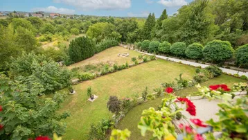 Panoramablick auf den weitläufigen Garten und die umliegende grüne Landschaft.