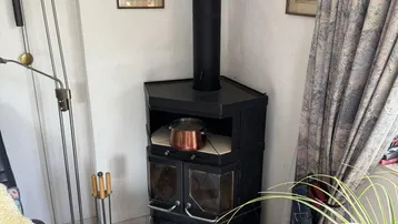 Gemütlicher Holzofen in einer Ecke des Wohnzimmers, bereit für kalte Tage.