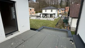 Blick von einem Flachdach auf benachbarte Häuser und einen gepflegten Garten.