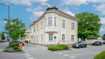 Historisches Eckgebäude mit klassischer Fassade und vielen Fenstern an einer städtischen Kreuzung.