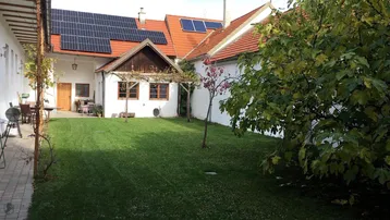 Grüner Innenhof mit Rasenfläche, Gebäuden mit Solarpaneelen und einem Essbereich im Freien.