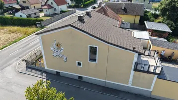 Seitenansicht des Hauses mit Sonnenuhr und Blick auf die Nachbarschaft.