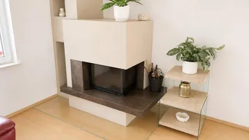 Moderner Kamin mit Glasbodenplatte und dekorativen Pflanzen in einem hellen Wohnzimmer.