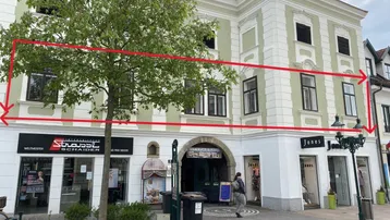 Fassade eines historischen Gebäudes mit Geschäften im Erdgeschoss und Wohnungen darüber.