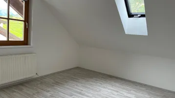 Helles Zimmer im Dachgeschoss mit Laminatboden, Fenster und Dachfenster, bietet Bergblick.