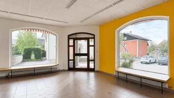 Großer offener Raum mit großen Bogenfenstern, gelben Wänden und Fliesenboden, ideal für Einzelhandel.