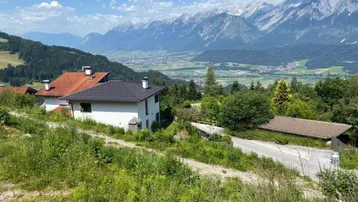 Modernes Haus in Hanglage mit Panoramablick auf die umliegende Bergwelt und das Tal.