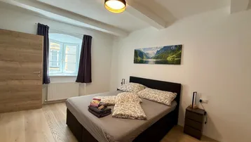 Helles Schlafzimmer mit Holzbalken an der Decke, Parkettboden und einem gemütlichen Doppelbett.