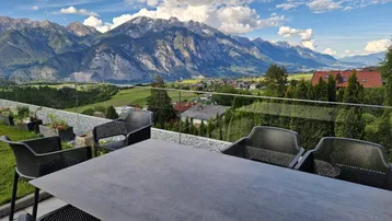 Große Terrasse mit Esstisch und Stühlen, die einen spektakulären Blick auf die Berge bietet.